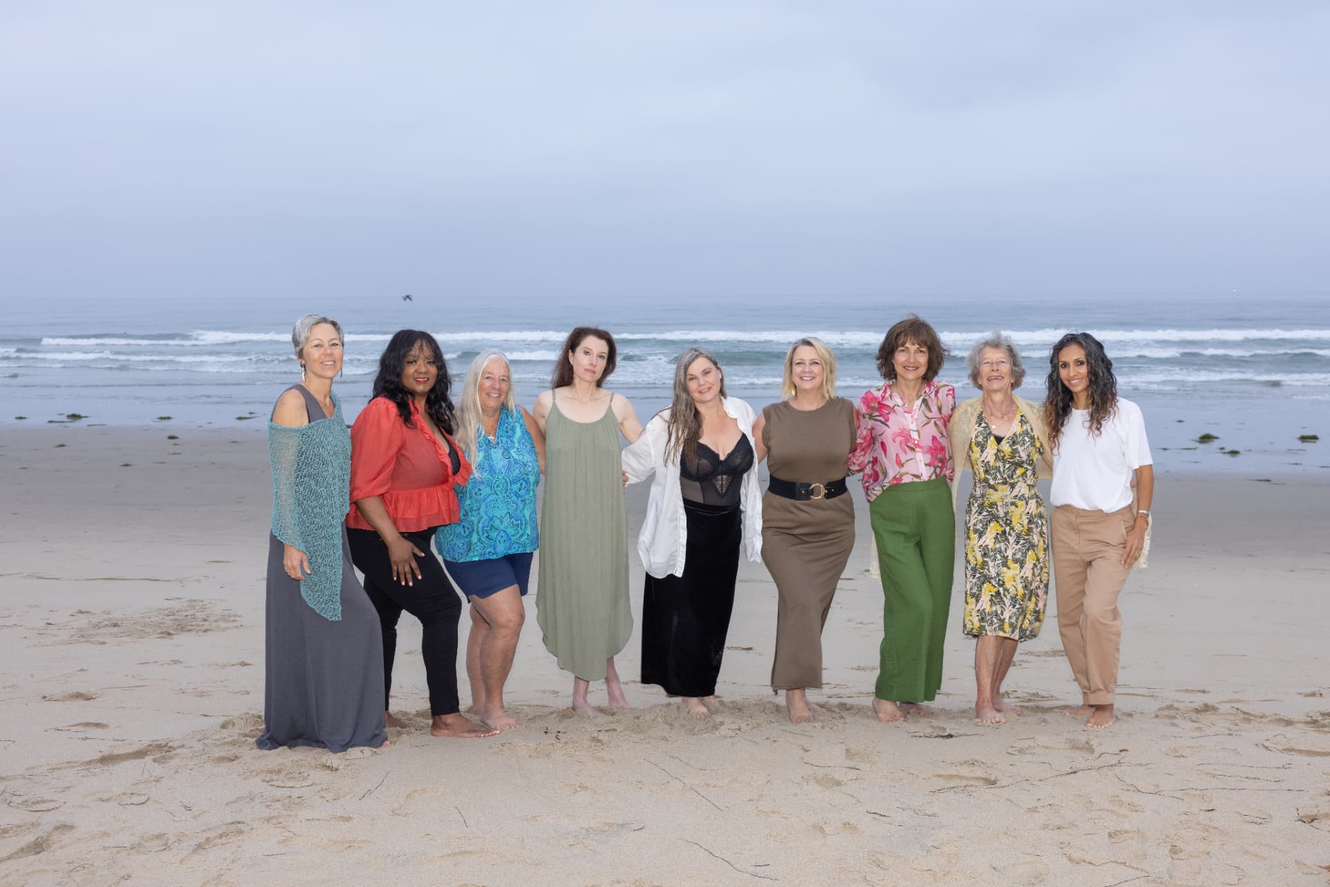 A circle of women standing together on a beach at dusk